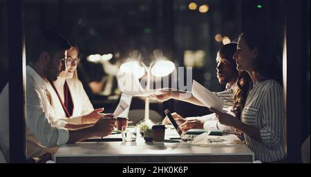 Dai un'occhiata a questi numeri. 4k filmati di un team di uomini d'affari che hanno una riunione a tarda notte nella sala riunioni. Foto Stock