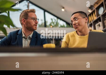 Businesspeople focalizzati che collaborano al nuovo progetto due giovani imprenditori che utilizzano il laptop mentre lavorano insieme in un ambiente di lavoro moderno giovane adulta Foto Stock