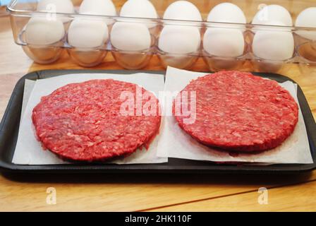 Polpettine di hamburger crudi freschi con uova crudi sullo sfondo Foto Stock