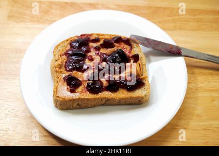 Preparazione di un burro di arachidi e sandwich di gelatina Foto Stock