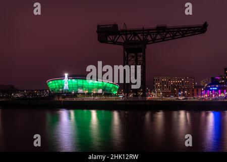 La Finnieston Crane sul fiume Clyde con l'arena coperta polivalente Hydro illuminata in verde sullo sfondo. Foto Stock