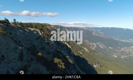 Scenario pittoresco della catena montuosa e valle ricoperta di alberi verdi contro il cielo blu con belle nuvole in estate. Incredibile Foto Stock