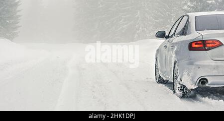 Auto argentata coperta di ghiaccio parcheggiata su strada coperta da neve, vista dettagliata da dietro, sfondo spazio vuoto per testo lato sinistro Foto Stock