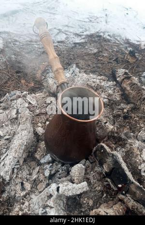 In una cezve di rame, il caffè viene preparato sulle calze calde di un fuoco, il vapore viene da esso, e la neve è intorno ad esso. Foto Stock