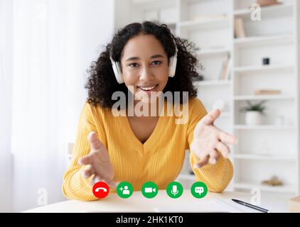 Visualizzazione a schermo verticale di una giovane donna nera felice in cuffie per videochiamare, utilizzando il computer da casa Foto Stock