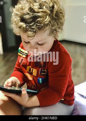 ragazzo di 3 anni che guarda il telefono Foto Stock