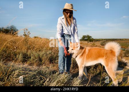 Donna che gioca con il divertente cane Akita Inu all'aperto Foto Stock