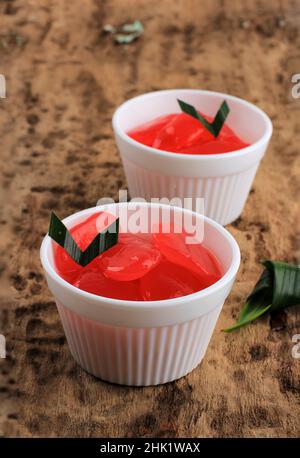 Manisan Kolang-Kaling o frutti di palma di zucchero conservati con colore rosso. Servito su ciotola bianca, tavolo di legno, fuoco selettivo Foto Stock