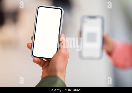 Maschio Hand Holding cellulare Scanning Code on Phone Indoor, Closeup Foto Stock