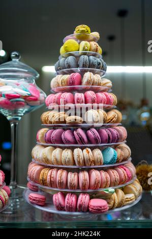 Negozio di dolciumi con colorata piramide di biscotti francesi macaron di notte Foto Stock