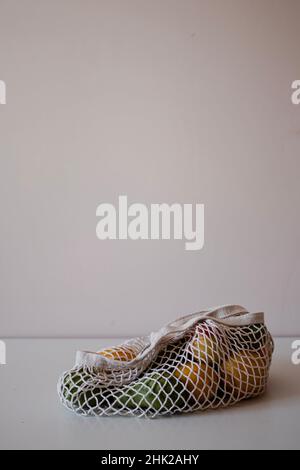 Molti frutti in una borsa eco-consapevole sono sdraiati sul tavolo. Superficie piana sana con spazio per la copia. Avocado, limoni, pesche, pere, arance. Foto Stock