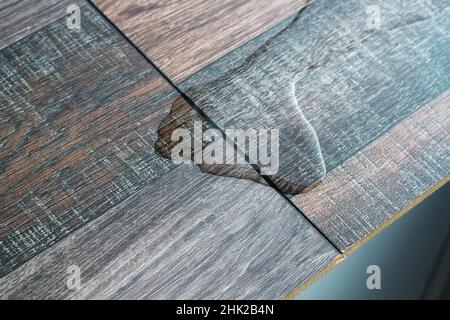 Laminato e acqua. Laminato impermeabile. I pavimenti in legno sono impermeabili all'umidità. I rivestimenti per pavimenti proteggono dall'acqua. Una pozzanghera sul pavimento. Foto Stock