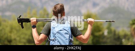 L'escursionista è in possesso di bastoni finlandesi per camminare fino alla cima della montagna Foto Stock