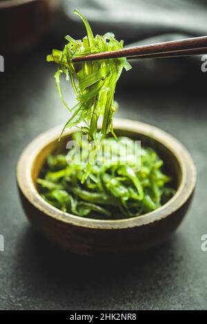 Wakame verde. Insalata di alghe in ciotola su un tavolo nero. Foto Stock