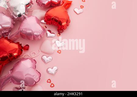 Sfondo romantico per matrimoni, San Valentino e compleanno. Palloncini a forma di cuore in argento e rosa, confetti cuore d'amore in metallo rosa. Foto Stock