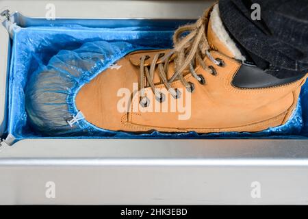 Copriscarpe e un clinthoper, un organizzatore per copriscarpe monouso in ospedale, un uomo mette su scarpe copriscarpe per la pulizia nella stanza, un Foto Stock