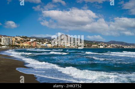 Vista della Malagueta, una delle spiagge della città andalusa di Malaga con onde, cielo blu e nuvole bianche. Foto Stock