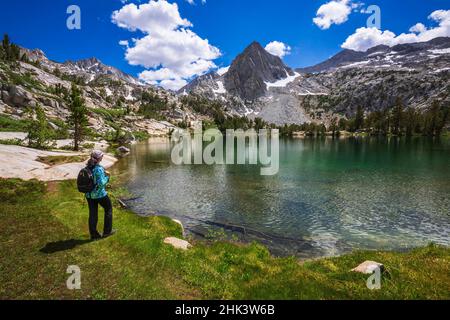 Escursionista sulle rive del lago Treasure, John Muir Wilderness, Sierra Nevada Mountains, California, USA. Foto Stock