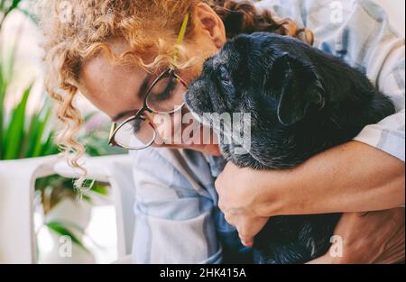 Amore persone e cane animale concetto con felice adulto caucasica donna e nero vecchio pug abbraccio e amare con tenerne insieme. I migliori amici per sempre Foto Stock