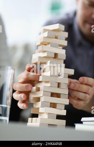 Giovane uomo che rimuove i blocchi di legno dal primo piano della torre giocattolo Foto Stock