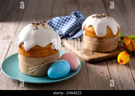 Tradizionale torta pasquale, uova colorate e tulipani su tavola di legno. Foto Stock