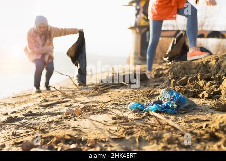 Due giovani volontari puliscono sacchetti di plastica da una spiaggia Foto Stock