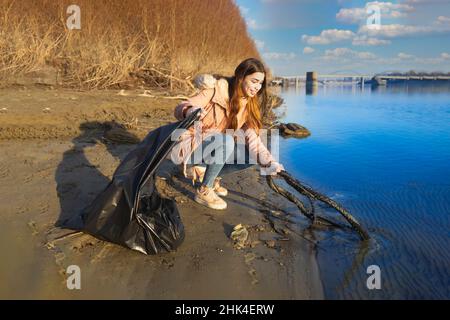 Giovane volontario pulisce l'acqua dai rifiuti Foto Stock