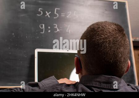Il bambino con il laptop calcola davanti alla lavagna Foto Stock