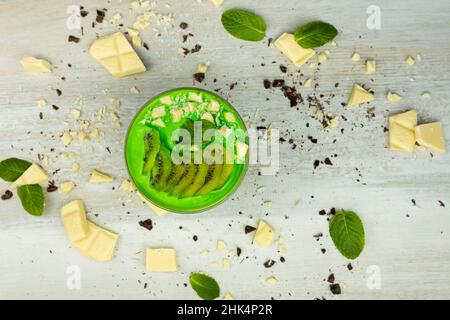 Frullato o budino con kiwi e cioccolato bianco servito in una ciotola per colazione. Foto con disposizione piatta Foto Stock