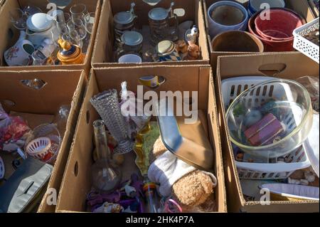 Scatole di cartone con vecchi articoli usati per la casa e stoviglie su una vendita garage o mercato delle pulci in un fine settimana di sole, fuoco selezionato, profondità di campo stretta Foto Stock