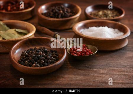 Varie spezie in piccole ciotole di legno su un tavolo rustico marrone scuro, concetto di cibo, fuoco selezionato, stretta profondità di campo Foto Stock