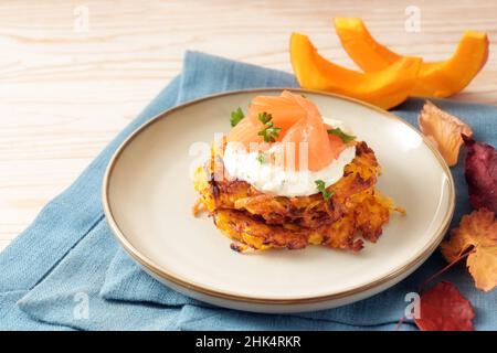 Frittelle di verdure o pancake di patate e kuri rosso squash con salsa di formaggio cremoso e salmone affumicato, antipasto autunnale per il Ringraziamento e Hallowee Foto Stock