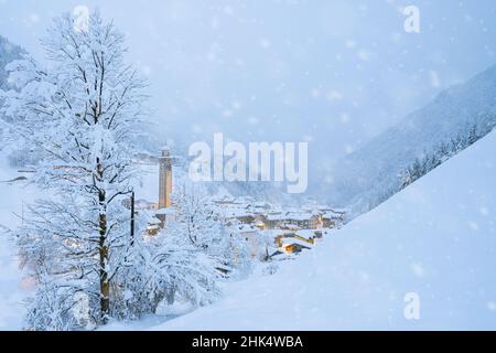 Fiocchi di neve che cadono su capanne di montagna nel fiabesco villaggio alpino a Natale, Valgerola, Valtellina, Lombardia, Italia, Europa Foto Stock