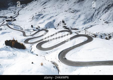 Auto che viaggia su curve di strada tortuosa nella neve, Passo Julier, distretto di Albula, Engadina, cantone di Graubunden, Svizzera, Europa Foto Stock