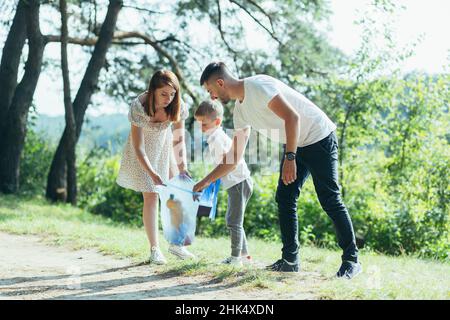 il volontario di famiglia pulisce i rifiuti in natura. Padre e madre, genitori, figli, figli volontari di famiglia in una giornata di sole ripulendo i rifiuti bo Foto Stock