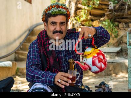 Uomo tradizionale vestito della tribù di fiori Qahtani, serve tè, ASiR Mountains, Regno dell'Arabia Saudita, Medio Oriente Foto Stock