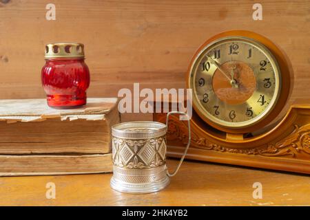 Un vecchio orologio in legno su una mensola con libri. Primo piano degli oggetti di casa Foto Stock