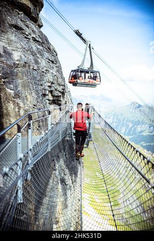 Una persona che guarda la funivia dal percorso emozionante della scogliera, Murren Birg, Jungfrau Region, Canton Berna, Svizzera, Europa Foto Stock