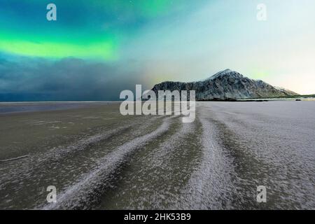 Sabbia congelata della spiaggia di Skagsanden sotto l'aurora boreale in inverno, Flakstad, contea di Nordland, isole Lofoten, Norvegia, Scandinavia Foto Stock