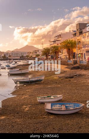 Vista delle barche sulla spiaggia a Baha de Arrecife Marina circondato da negozi, bar e ristoranti al tramonto, Arrecife, Lanzarote, Isole Canarie, Spagna Foto Stock