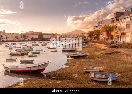 Vista delle barche sulla spiaggia a Baha de Arrecife Marina circondato da negozi, bar e ristoranti al tramonto, Arrecife, Lanzarote, Isole Canarie, Spagna Foto Stock