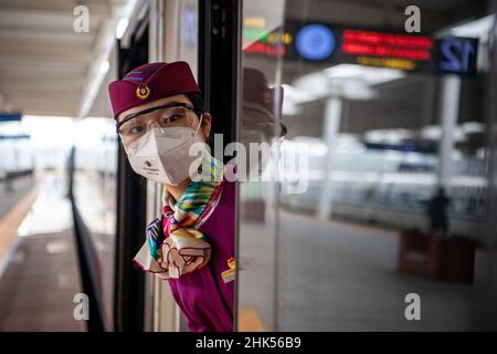 (220202) -- CHONGQING, 2 febbraio 2022 (Xinhua) -- Lin Mengfan si prepara al lavoro prima della partenza di un treno superveloce alla stazione ferroviaria di Chongqing North a Chongqing, Cina sudoccidentale, 2 febbraio 2022. Nato nel 2000, Lin Mengfan è una nuova superba stazione per un treno superveloce Fuxing sulla ferrovia di Chendu-Chongqing. Nel frattempo, Lin è al servizio della corsa di corsa del festival di primavera per la prima volta nella sua carriera. Nel caso in cui ci sia un passeggero che ha bisogno di aiuto a bordo, Lin ha preparato con lei una custodia versatile per attrezzi. Nella custodia sono gli adesivi colorati per i passgenger di marcare i loro bagagli, cartoni animati adesivi per p Foto Stock