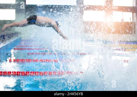 L'uomo sfocato non è un atleta che si tuffa in piscina in acqua. Foto Stock