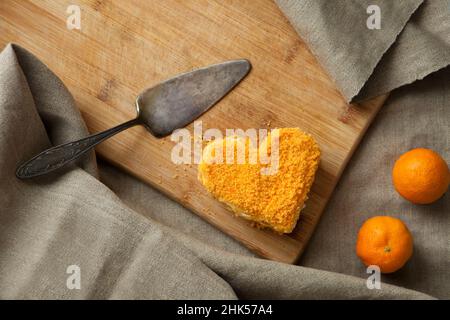 Torta a forma di cuore con tangerini d'arancia su tavola di legno. Dolce carota per San Valentino Foto Stock