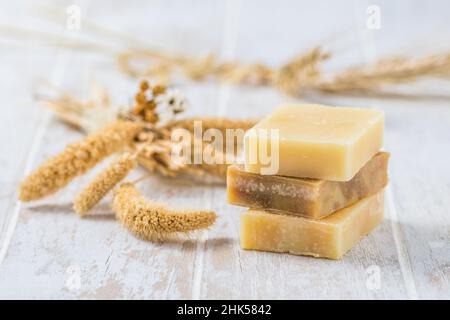 Tre pezzi di sapone naturale su sfondo bianco in legno, concetto di benessere Foto Stock