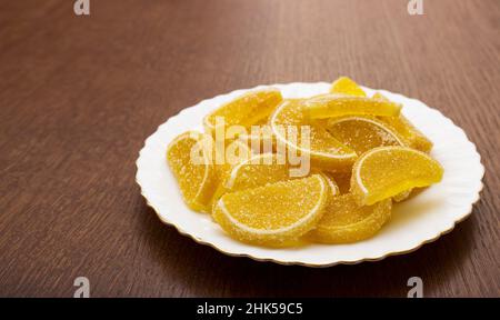 marmaliate le fette di limone su un piatto bianco su un tavolo di legno primo piano Foto Stock