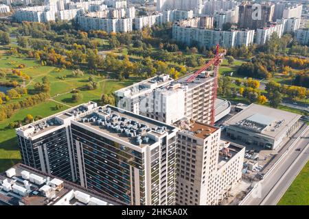 Veduta aerea della gru di sollevamento torre e del telaio in cemento di un alto edificio residenziale in costruzione in una città. Sviluppo urbano e reale Foto Stock