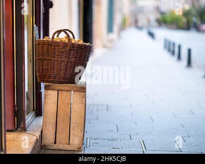 Un cestino pieno di noci di fronte ad un negozio su una strada a Nancy (Francia), nuvoloso giorno d'estate Foto Stock