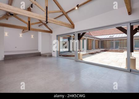 Trumpington, Cambridgeshire - Maggio 04 2017: Elegante lusso minimalista contemporaneo open space soggiorno all'interno di moderno fienile conversione con travi a vista, Foto Stock
