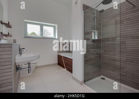 Trumpington, Cambridgeshire - Maggio 04 2017: Camera da bagno minimalista di lusso contemporaneo con doccia all'interno di una nuova casa con pareti piastrellate e dipinte di bianco Foto Stock